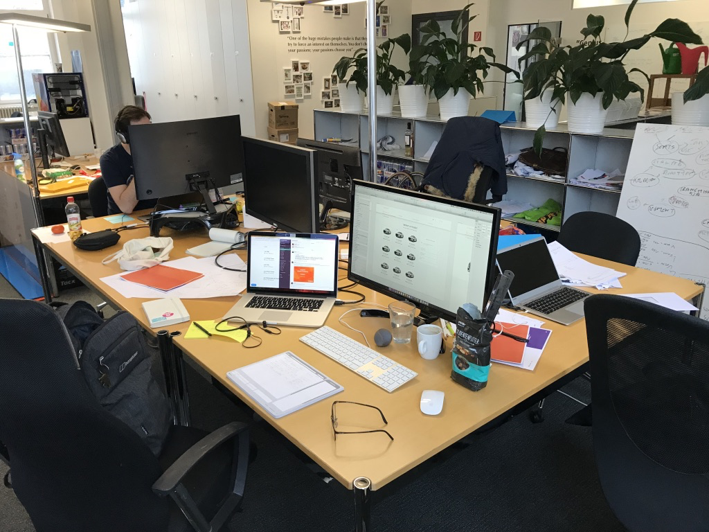 Three cramped desks where people are working on building a website