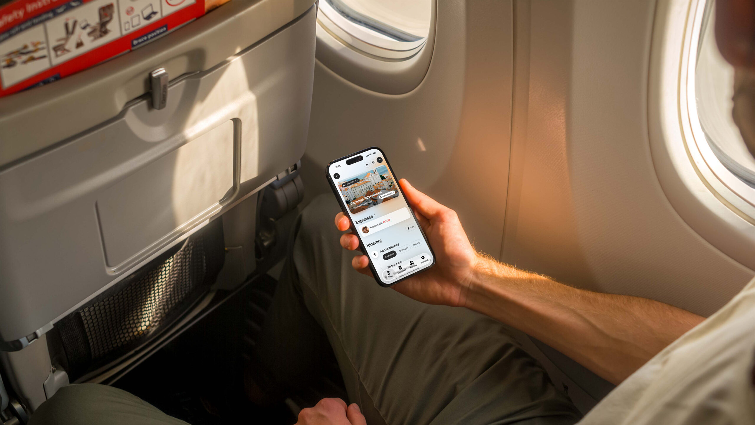 A person sat on a passenger place whilst holding their phone with the Trippy app open